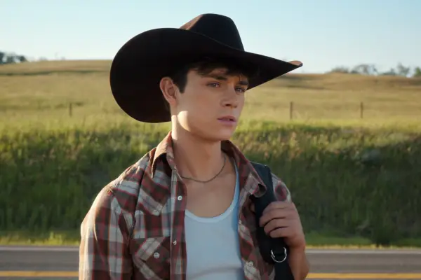 Ashby Gentry as Alex in My Life with the Walter Boys. He is wearing a white vest, a patterned shirt and a brown cowboy hat.