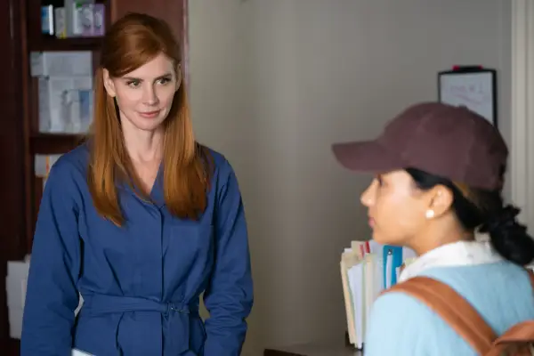 Katherine wearing a blue boiler suit, smiling as she looks at Jackie who can be seen wearing a brown cap.