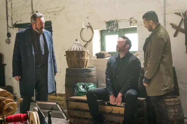 Frank (Francis Magee), Donal (Diarmaid Murtagh) and Asim (Assad Raza) in The Tourist gathered together in a white bricked building