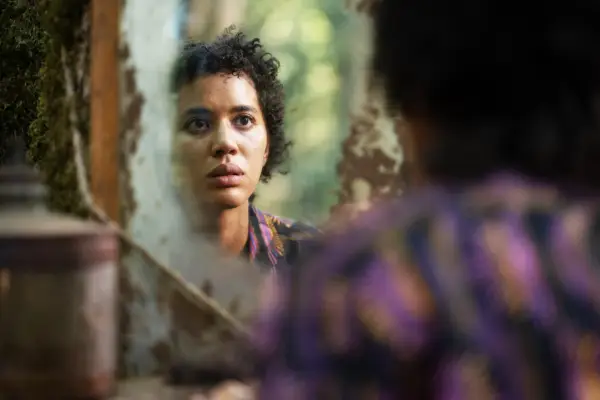 Teen Taissa looking at herself in the mirror in the woods with a shocked expression on her face