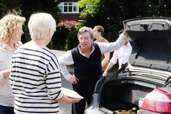 Isobel Middleton as Kay Linnell opening the boot of her car while talking to people