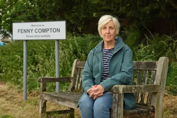 Julie Hesmondhalgh in a promo shot for Mr Bates vs The Post Office. She is sat down on a bench and looking towards a camera
