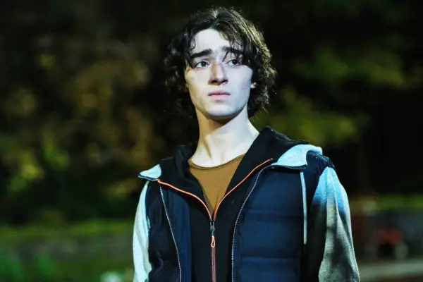 Tareq Al-Jeddal as Jack Farman-Hoyle, stood outside, trees and grass behind, he looks scared