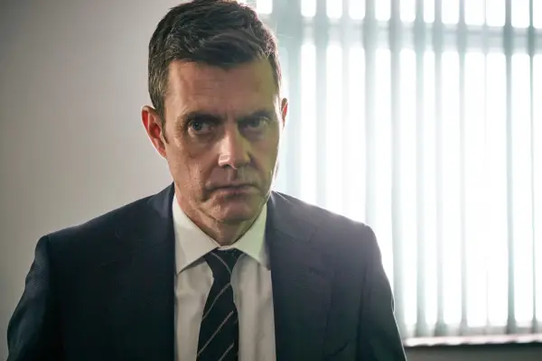 Paul Higgins as Kirk in Cold Call, wearing a suit