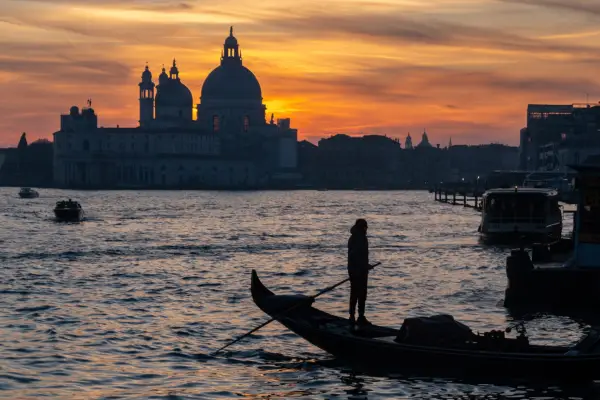 Basilica di Santa Maria della Salute church and a typical gondola boat during sunset are seen in Venice, Italy, on January 30th, 2024. Basilica di Santa Maria della Salute church is a Baroque masterpiece with an octagonal design, a majestic dome, and notable artworks, serving as a symbol of gratitude in the city