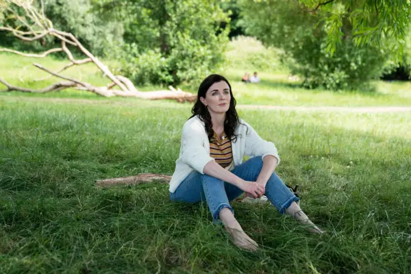 Aisling Bea sat on the grass outside in Alice & Jack