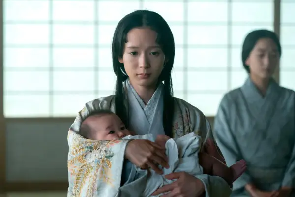 Moeka Hoshi as Usami Fuji holding a newborn baby while kneeling down and looking on the floor.