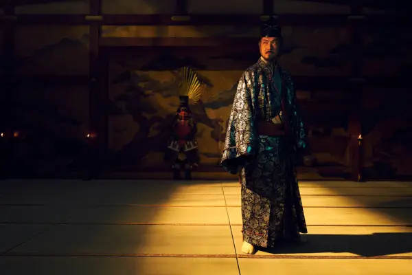 Takehiro Hira as Ishido Kazunari standing in natural light in the middle of a dimly lit room, wearing traditional Japanese dress.