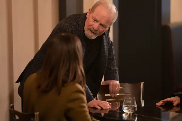 Peter Mullan stars in Payback, leaning on a table
