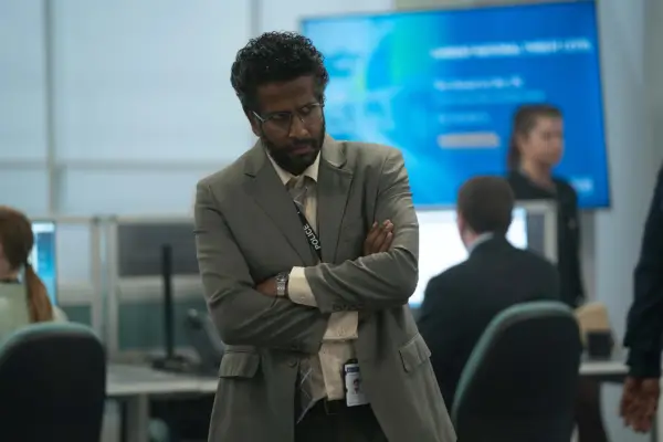 Prasanna Puwanarajah stars in Payback, wearing a grey suit with her arms crossed