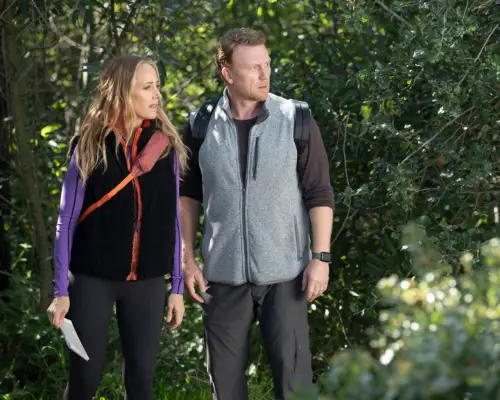Kim Raver as Dr Teddy Altman and Kevin McKidd as Dr Owen Hunt stand in outdoor wear in a forest setting for Grey