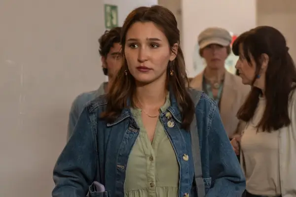 Thais Martin plays Caitlin in Frauds; seen here walking down a corridor looking worried