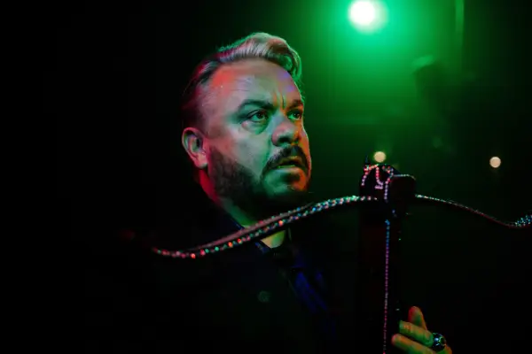 Lee Boardman plays Craig in Frauds; his character is seen here on-stage with a bright green light in the background