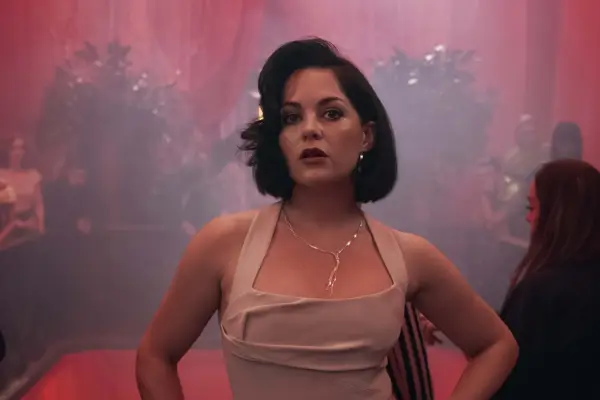 Dee Dee Harrison wears a glamorous white dress in a busy nightclub setting