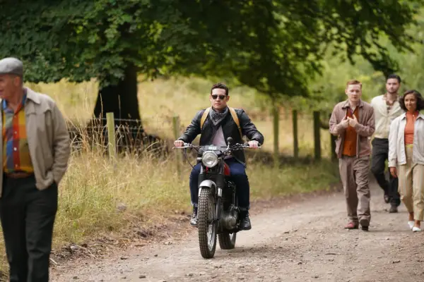 Will from Grantchester riding past a crowd on a motorbike