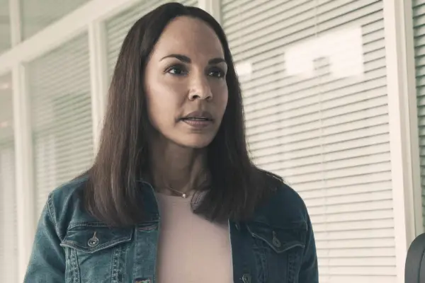 Amanda Brugel as Rita, stood on a porch, looking ahead