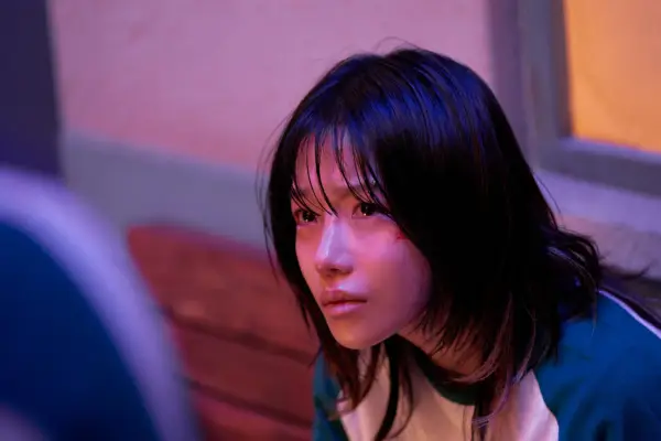Jo Yu-ri as Jun-hee in Squid Game season 3, looking up at someone with a solemn expression on her face