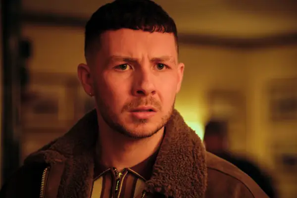 Jack James Ryan as John Trowbridge standing and looking at someone very angrily in Passenger.