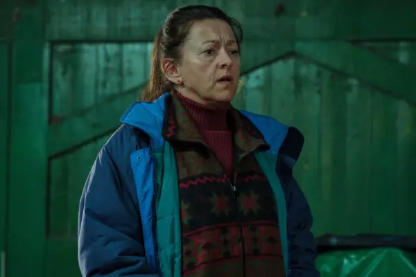 Jo Hartley as Linda wearing a jacket and standing in the middle of a warehouse looking confused in Passenger.