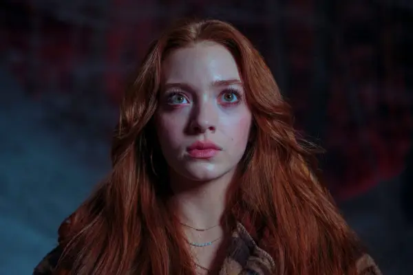 Rowan Robinson as Katie Wells staring up at the sky stood in the middle of a forest in the dark in Passenger.