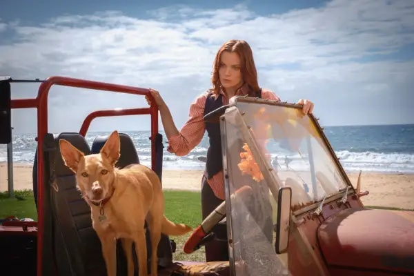 Anna Samson as DI Mackenzie Clarke looking into her car with a blank look on her face where a dog sits, with the beach and sea in the background.