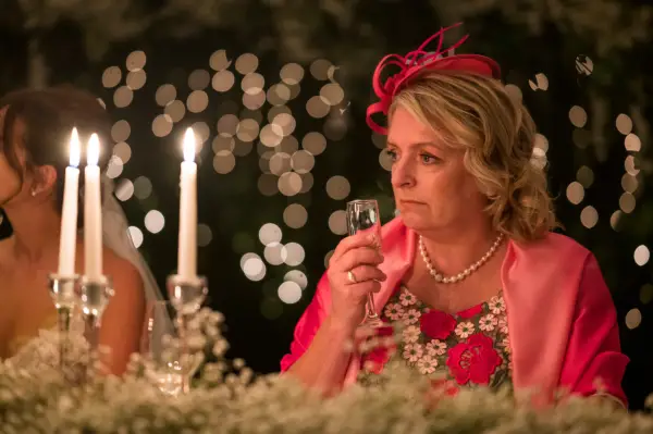 Claire Rushbrook as Caryl in Wilderness wearing a flowery dress and pink hat