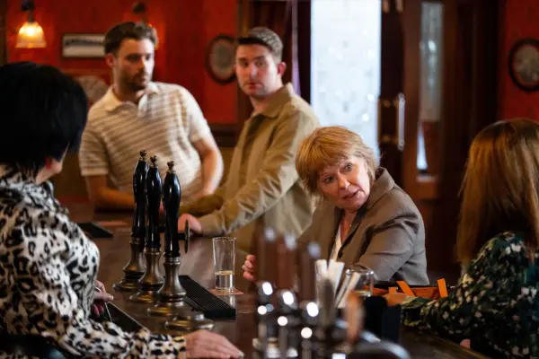 Johnny and Callum at the bar looking on as Julie speaks in EastEnders