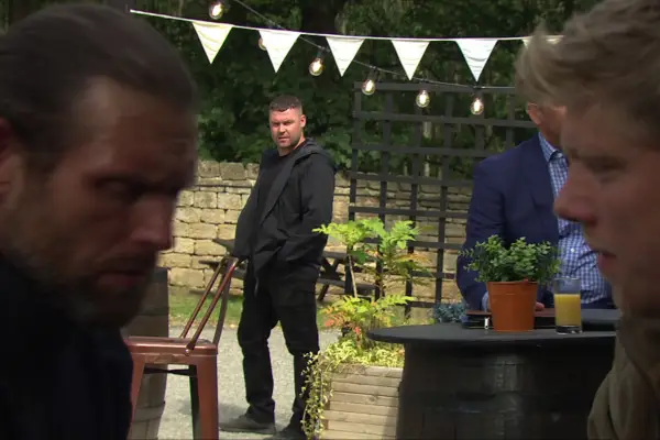 Aaron looking on at Kev and Robert in Emmerdale