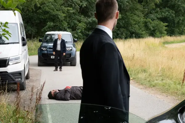 Joe looking at Caleb in the near-distance with Jimmy laying unconscious in the road in Emmerdale