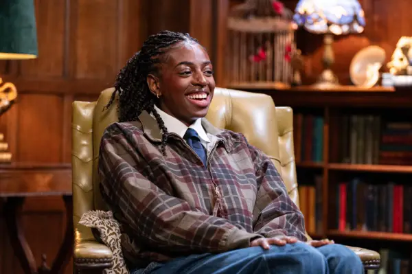 Cat Burns sat down in a yellow chair, smiling ahead.