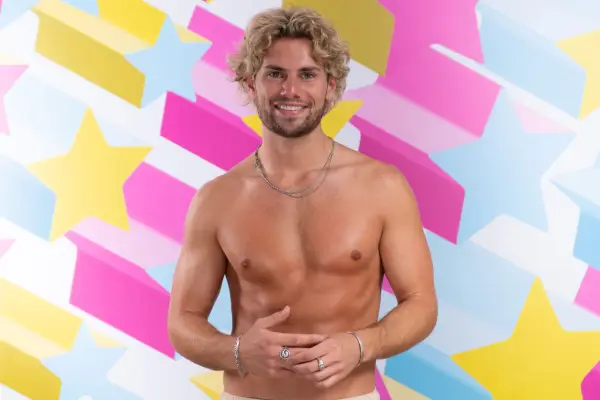 Love Island: All Stars contestant Joe Garratt posing shirtless in front of a multi-coloured star backdrop
