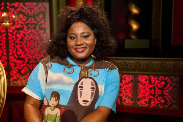 Susan Wokoma in the Taskmaster studio, wearing a Spirited Away T-shirt, looking into the camera and smiling