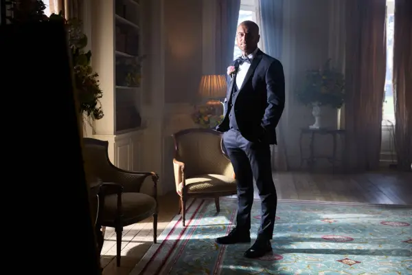 Joe wearing a black tuxedo, pictured in a dimly lit room.