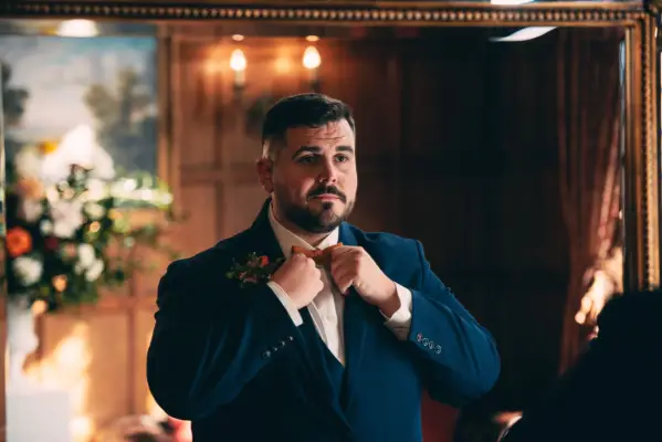 Dean pictured doing up his tie as he looks ahead.