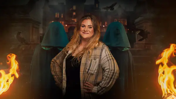 Charlie for The Traitors season 2. She is wearing a plaid shirt and black t-shirt with her hands on her hips