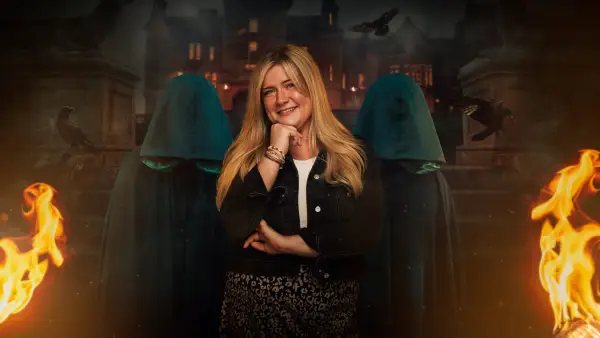 Evie for The Traitors season 2. Evie is wearing a black jacket and white t-shirt with her hand resting on her chin