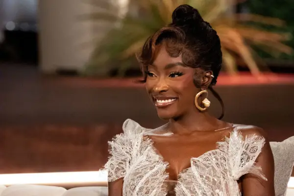 Chelsea Lazkani wearing a white gown, smiling across at something.