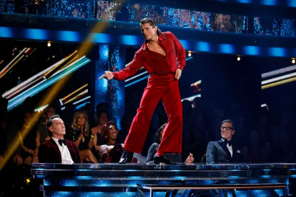Lewis Cope wearing a red outfit, stood on the judges table.