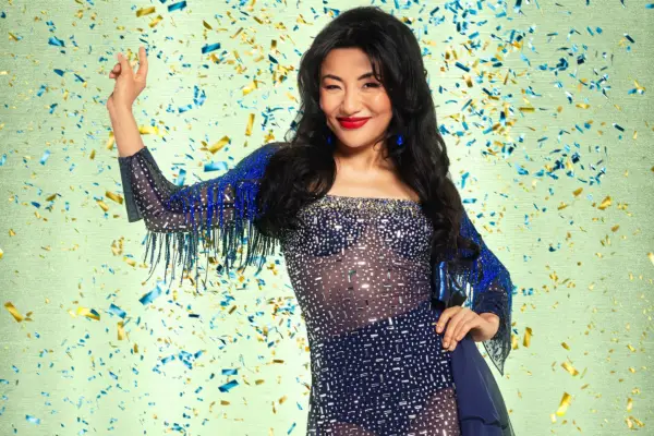 Nancy Xu wearing a dark blue sparkly dress, smiling ahead with a wink.