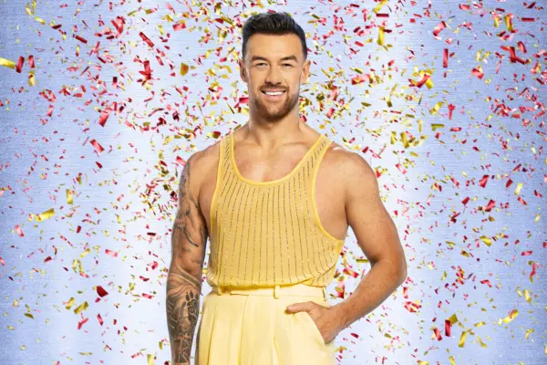 Kai Widdrington wearing a yellow vest top and trousers, smiling ahead.