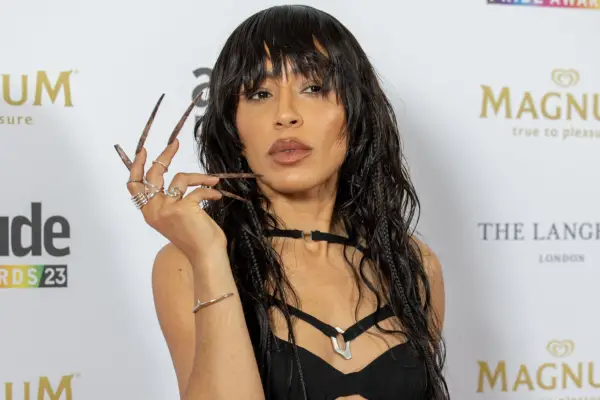 Loreen posing for a photo with her hand towards her face. She has a wet hair style with her fringe covering the top of her head.