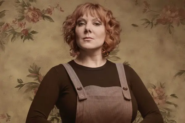 Sophie Willan in a black long-sleeved t-shirt and dungaree. She has ginger hair that comes up to her chin.