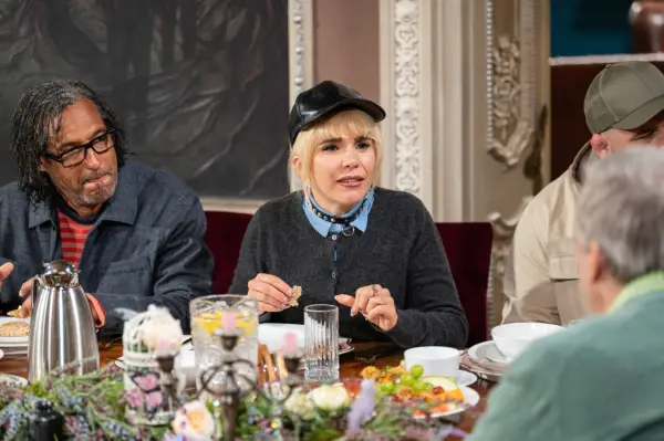 Paloma Faith sits at a breakfast table wearing a black cap and engages in conversation with other contestants on The Celebrity Traitors.