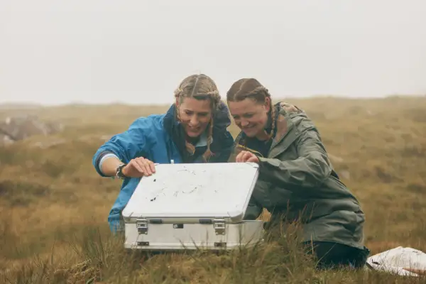 Jen and Beth on 007: Road To A Million looking into a silver case