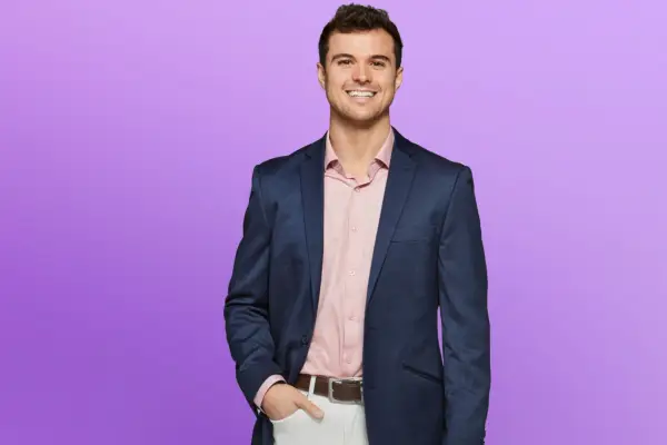 Chase wearing a pink shirt and blue blazer, smiling ahead.