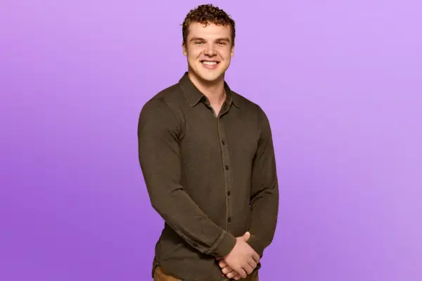 Jensen wearing a dark brown shirt, smiling ahead.