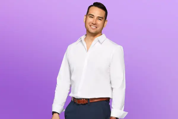 Mike wearing a white shirt and blue trousers, smiling ahead.