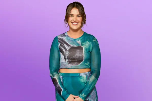 Aza wearing a blue mesh top and skirt, smiling ahead.