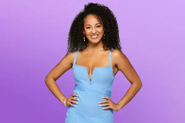 Kaylen wearing a light blue dress, smiling ahead with her hands on her hips.