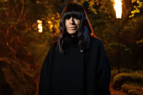 Claudia Winkleman wearing a black jacket, smiling.